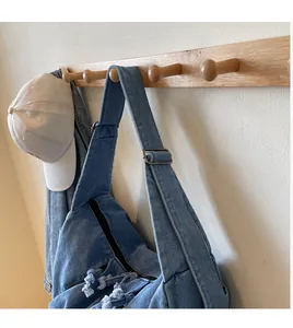 Detail of blue denim crossbody bag featuring adjustable wide strap and side drawstring design