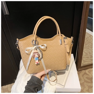 Close-up of khaki woven quilted tote bag with silk bow charm and shoulder strap detail