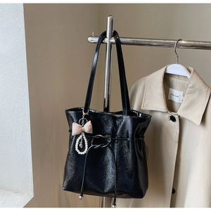 Détail du sac cabas noir brillant avec perles et breloque en forme de nœud à carreaux