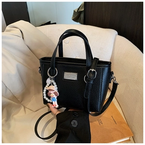 Close-up of black lychee grain PU leather bucket bag with silver metal plate and charm
