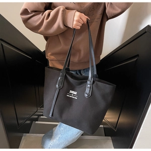 Close-up of a black canvas tote bag featuring a white SOBAG logo on an urban staircase