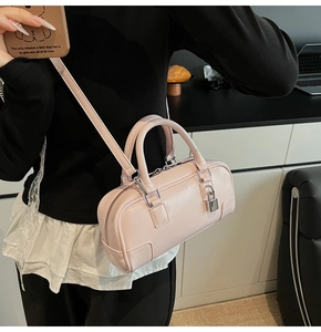 Detail of light pink Boston handbag with silver metal lock and textured leather finish
