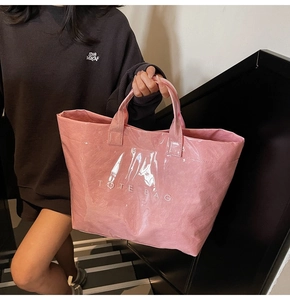 Vista dettagliata della borsa tote rosa lucida con grande scritta TOTE BAG sulle scale