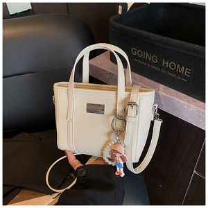 Detail of off-white lychee grain leather bucket bag with cute pearl charm and metal logo