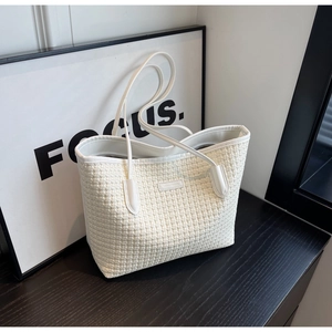 Detailed view of white woven tote bag texture with leather piping on a wooden surface