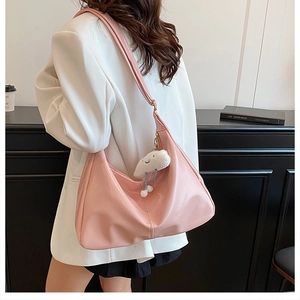 Detail of pink PU leather half-moon tote bag with cute cloud plush charm on a shoulder strap