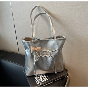 Dettaglio della borsa tote argento metallizzato con trama a pieghe e ciondolo di perle