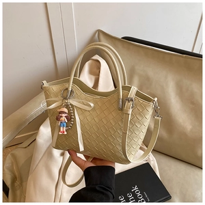 Detail of cream woven bucket bag with ribbon bow and a cute cartoon pendant charm
