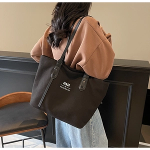 Lifestyle shot of large black canvas tote bag with shoulder strap and slogan print
