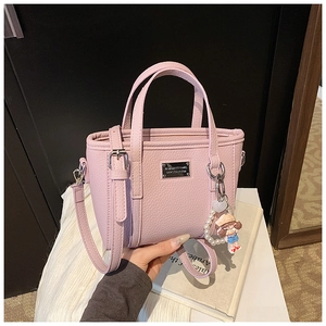 Detailed view of pink lychee leather mini bucket bag with pearl pendant and metal plaque