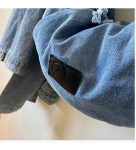 Detail of light blue denim fabric with leather brand tag and stylish frayed edge design