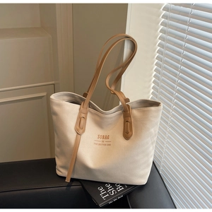 Close-up of large canvas tote bag with brown leather straps and SOBAG logo design
