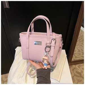 Detailed macro of pink litchi grain bucket bag with pearl charm and metal logo