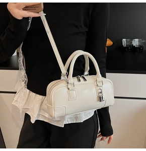 Close-up of cream Boston handbag with silver padlock detail and adjustable strap