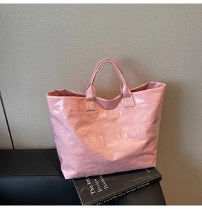 Dettaglio della borsa tote rosa stropicciata con finitura lucida e scritta bianca