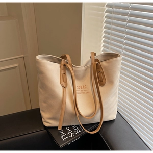 Detail of cream canvas tote bag with brown leather handles in natural sunlight
