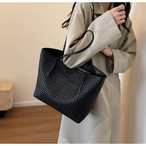 Close-up of black woven leather tote bag texture with minimalist logo patch for daily commute