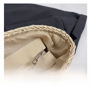Detailed close-up of straw tote bag with smooth metal zipper and beige fabric lining