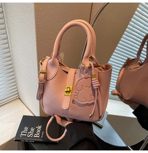 Detailed close-up of pink litchi grain leather bucket bag with gold lock and dog charm