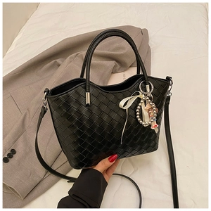 Detail of black woven leather bucket bag with cute charm and adjustable strap
