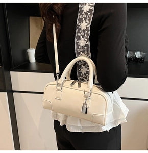 Detail of cream leather boston bag with floral lace strap and silver padlock charm