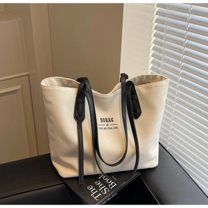 Close-up of beige canvas tote bag with black straps and SOBAG BE THE BETTER ONE print