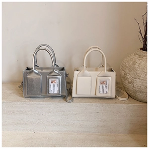 Detail of minimalist bucket bag in silver and beige with front card slots and top handles