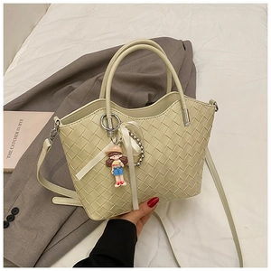 Detail of cream green quilted bucket bag with gold handle and woven texture design