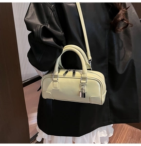 Detail of light green Boston bag with silver zippers, padlock charm, and stitched corners