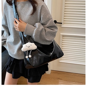 Detail view of large black PU leather tote bag with cute cloud plush charm on a model