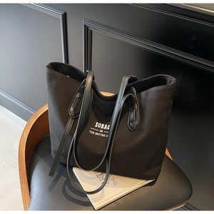 Detail of minimalist black canvas tote bag with SOBAG white lettering on a chair