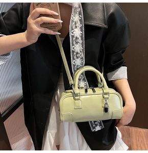 Close-up of stylish light green leather mini Boston bag with silver hardware on model