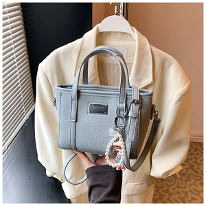 Detail of light blue lychee pattern crossbody bag with pearl charm and metal logo plate