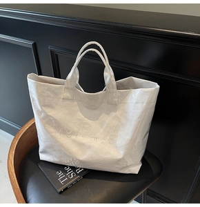 Dettaglio della borsa tote bianca con trama impermeabile pieghettata e stampa TOTE BAG