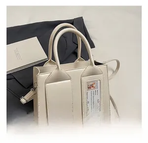 Close-up of cream bucket bag with transparent card slot on grey blazer background