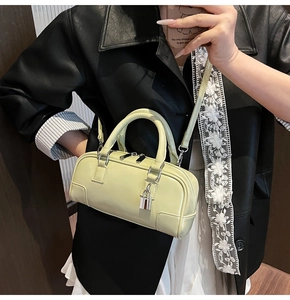 Detail of pistachio green Boston bag with dual handles and silver zipper hardware