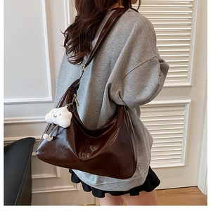 Detail of deep brown glossy tote bag featuring a cute white plush cloud pendant charm