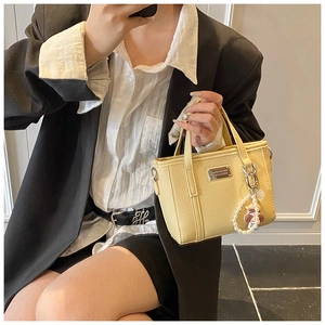 Detail of yellow lychee grain leather bucket bag with silver hardware and pearl bear charm