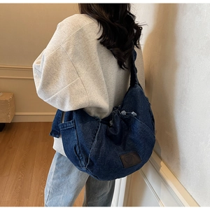 Detailed view of oversized denim crossbody bag with vintage wash and leather patch