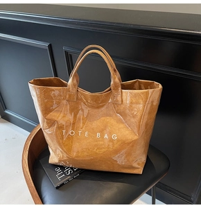 Dettaglio della borsa tote marrone lucida sulla sedia con texture e logo