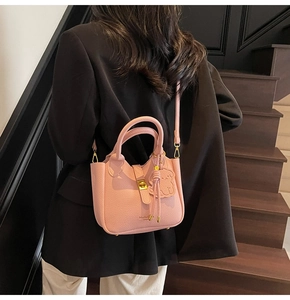 Pink lychee leather bucket bag with gold hardware and dog charm on a model