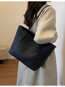 Grande borsa tote nera intrecciata minimalista indossata da una modella di moda