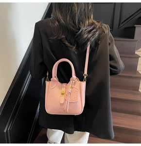 Pink lychee texture leather bucket bag with gold clasp and bear charm on model