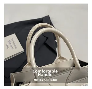 Detail view of comfortable round handles and fine stitching on a beige bucket bag
