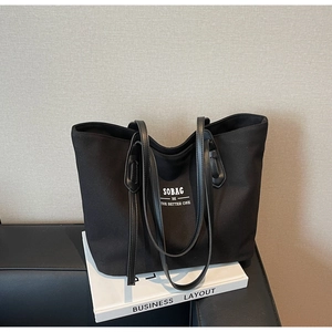 Detail of a large black canvas tote bag showing the white SOBAG brand slogan on the front