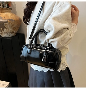 Detail of black glossy boston handbag with silver metal lock and adjustable strap
