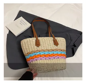 Dettaglio della borsa a secchiello in paglia intrecciata con strisce colorate e manici marroni