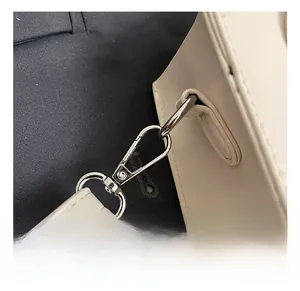 Close-up of durable silver metal hook and D-ring on white leather bucket bag strap