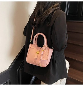 Detail of pink lychee leather bucket bag with metal twist lock and bear charm