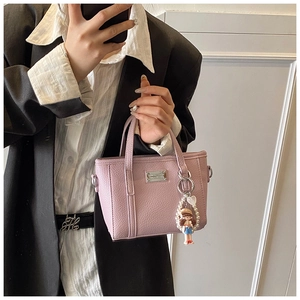 Detail of pink lychee leather mini tote bag with pearl cartoon charm on a model